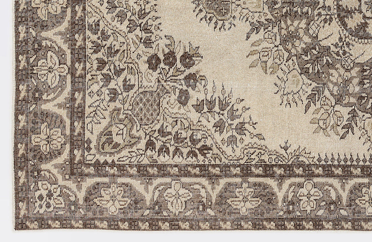 Beige and dark brown rug with a traditional floral medallion pattern and a detailed geometric border.