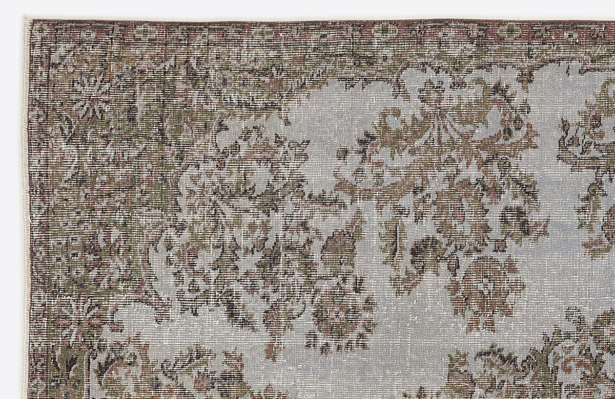 Distressed sage green and grey rug with a faded traditional floral medallion pattern.
