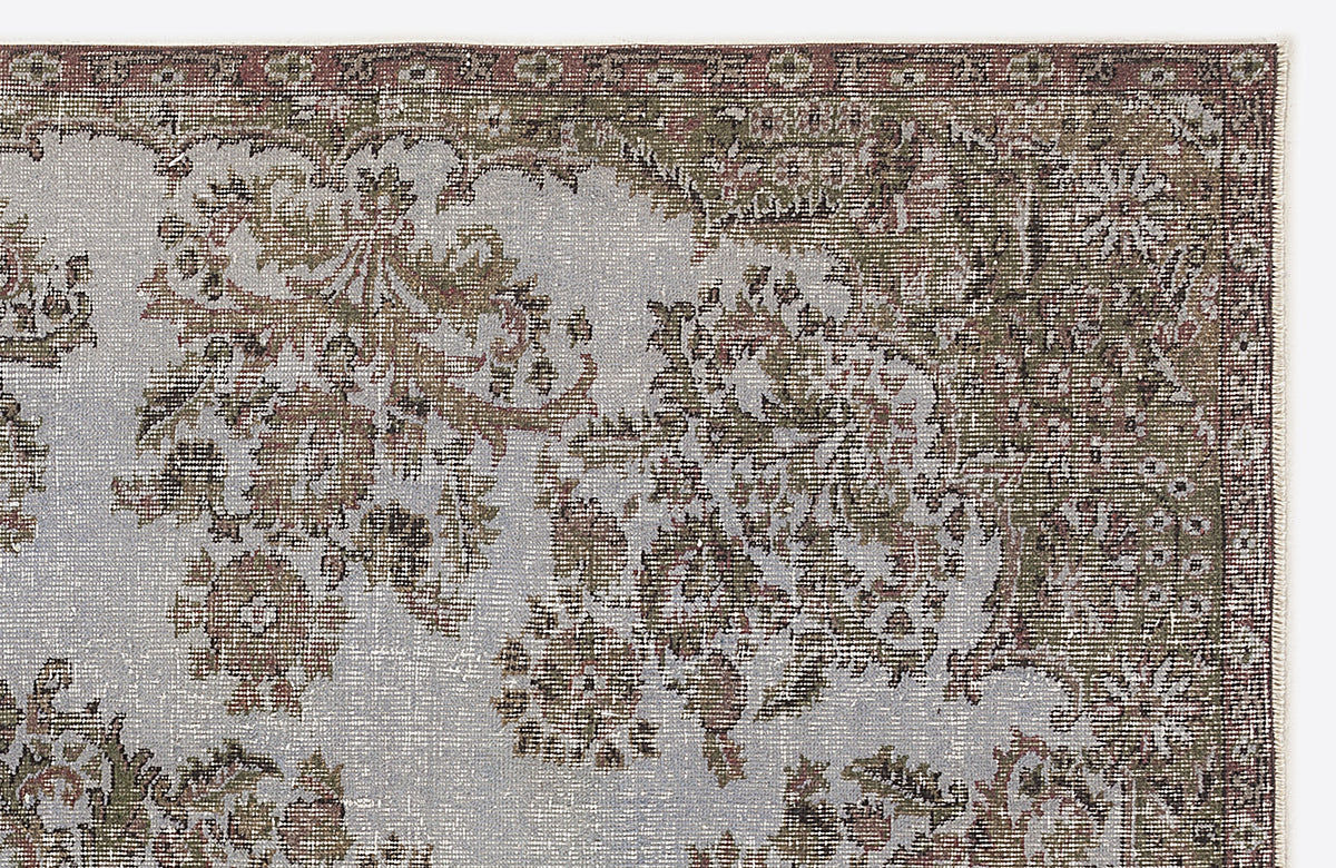 Distressed vintage-style rug with sage green, grey, and rust floral medallion patterns on a light grey background.