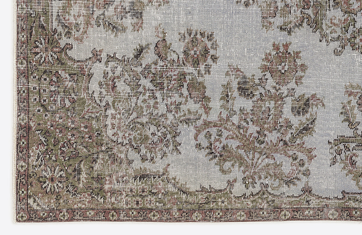 Distressed light blue rug with a faded floral medallion pattern in olive green and brown tones.