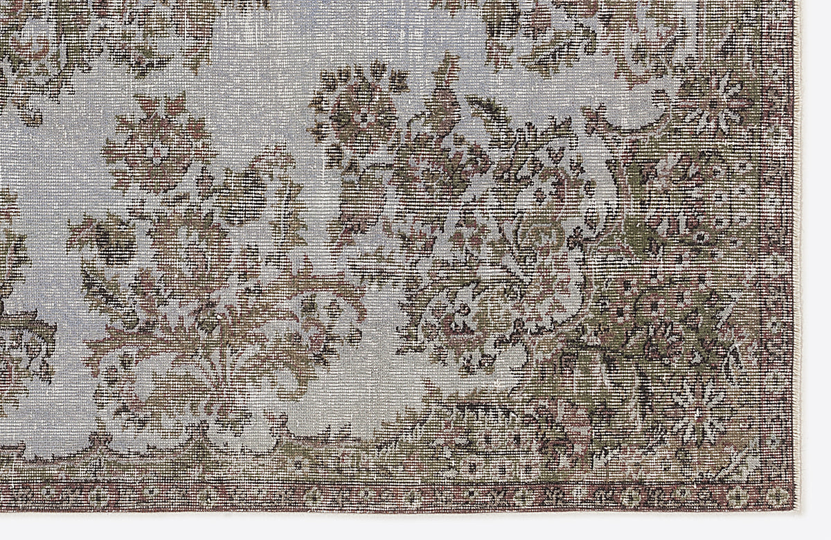Distressed light blue rug with a faded floral medallion pattern in olive green and brown tones.