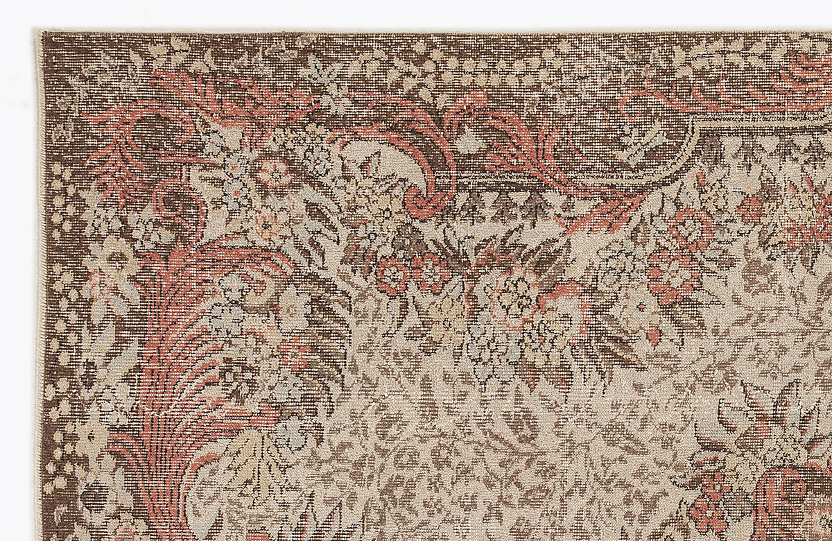 Brown, beige, and terracotta traditional rug with a dense, distressed floral and vine pattern.