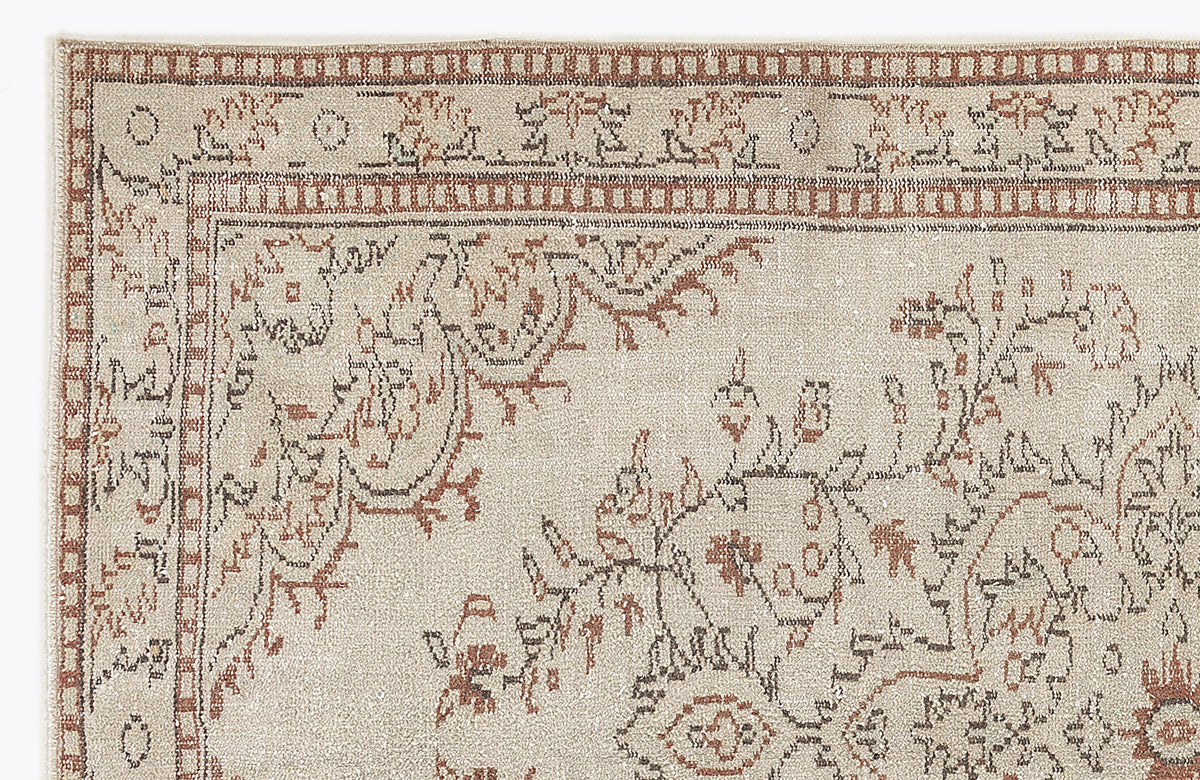 Beige rug with a distressed terracotta and charcoal floral medallion pattern and a geometric border.