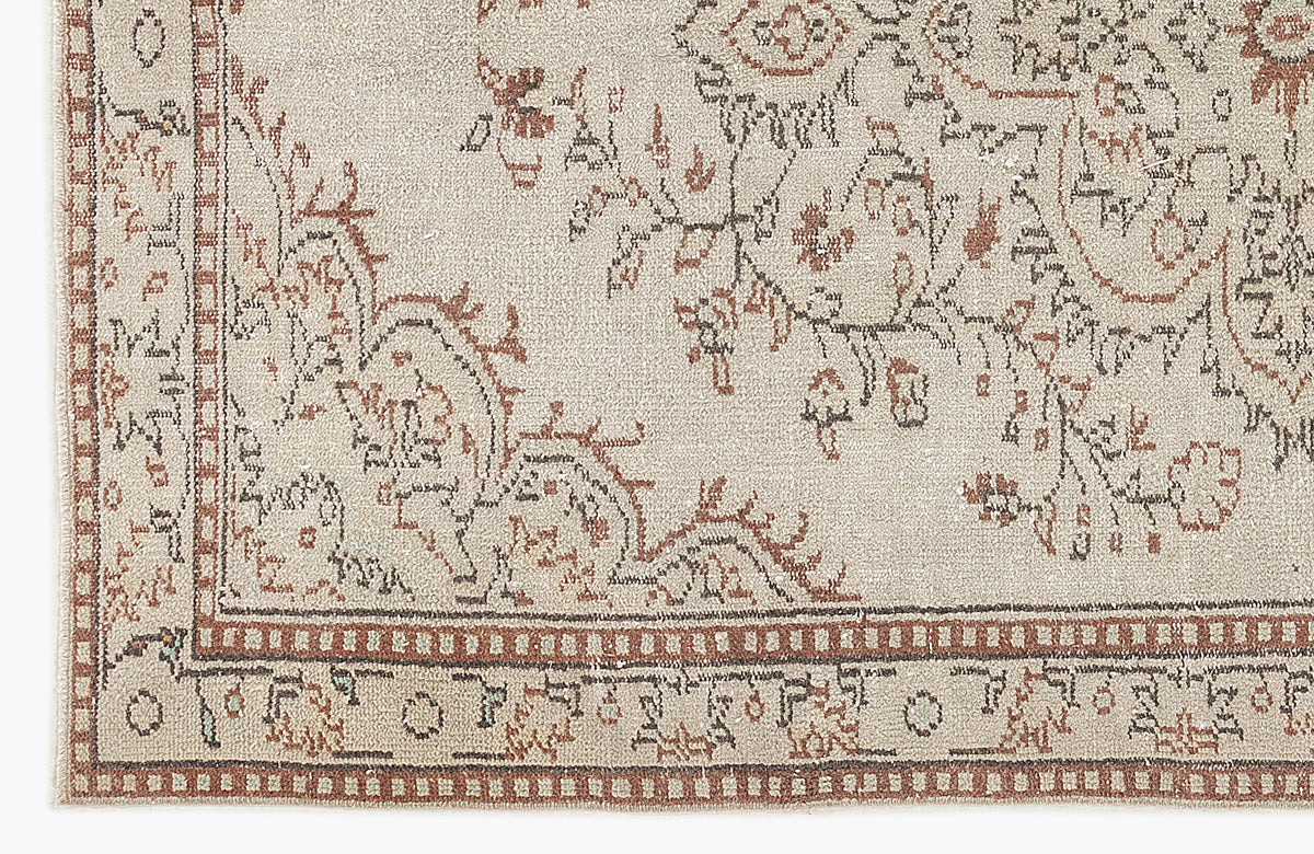 Beige rug with a distressed brown floral medallion pattern and a geometric border.