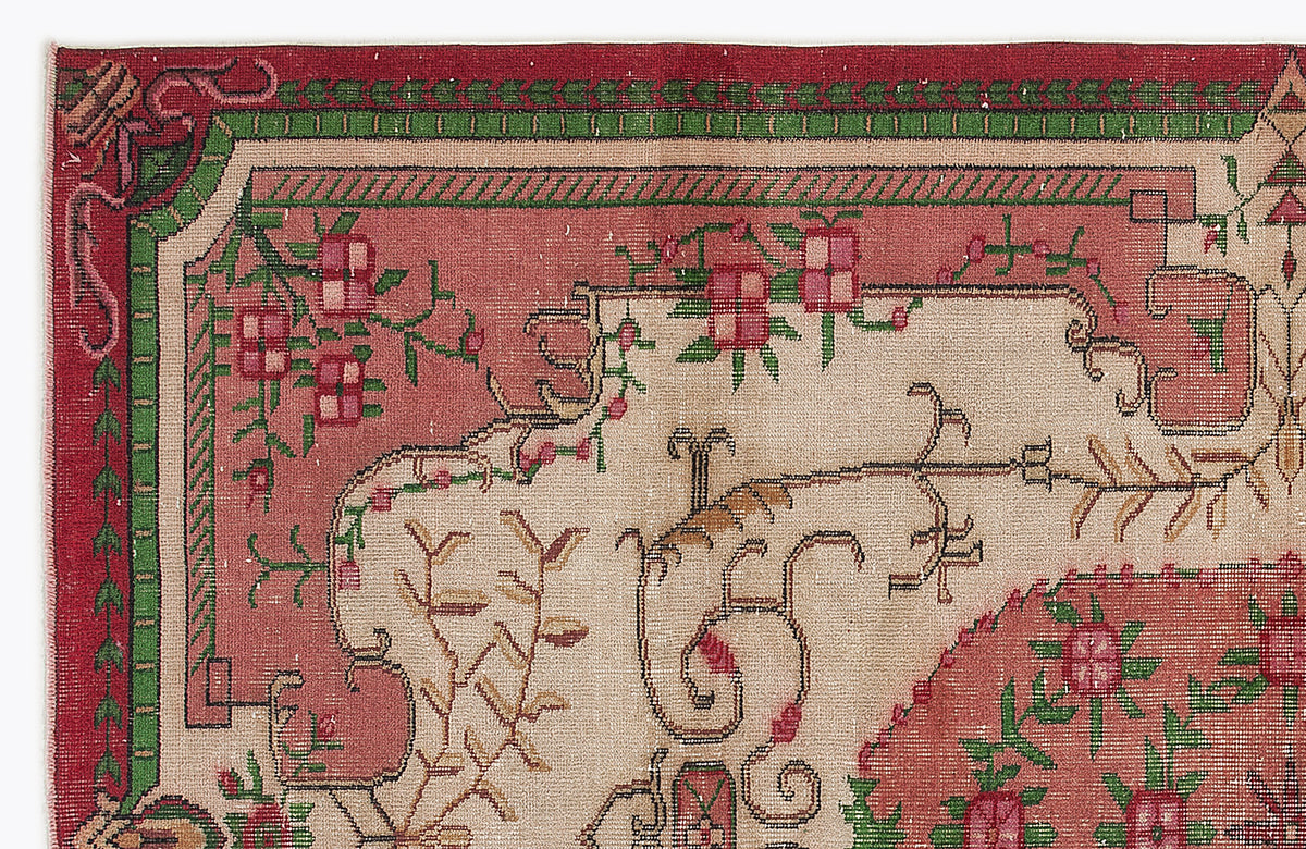 Vintage-style rug with a beige center, red border, and green and pink floral vine motifs.