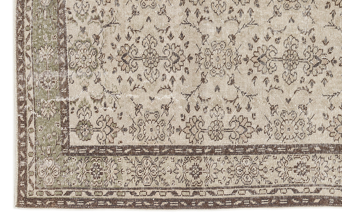 Beige and sage green vintage-style rug with a distressed floral medallion pattern and a dark brown geometric border.