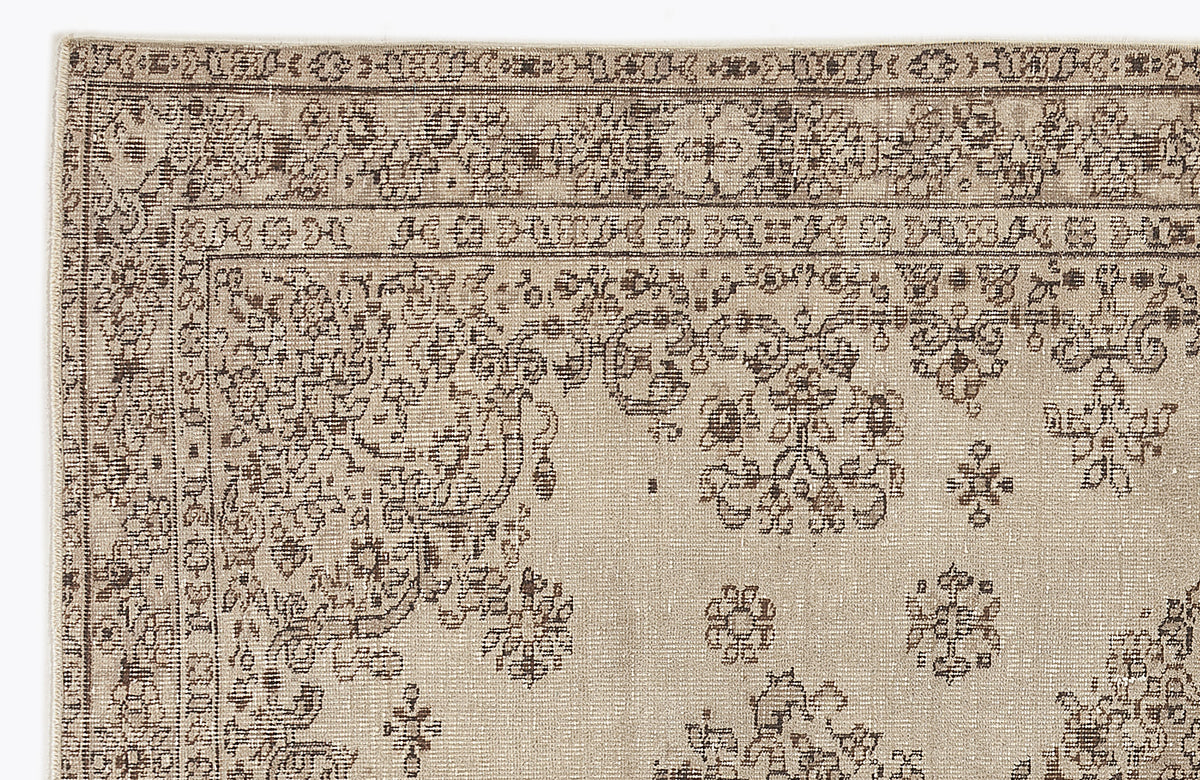 Beige and brown vintage-style rug with a distressed floral medallion pattern and a decorative geometric border.