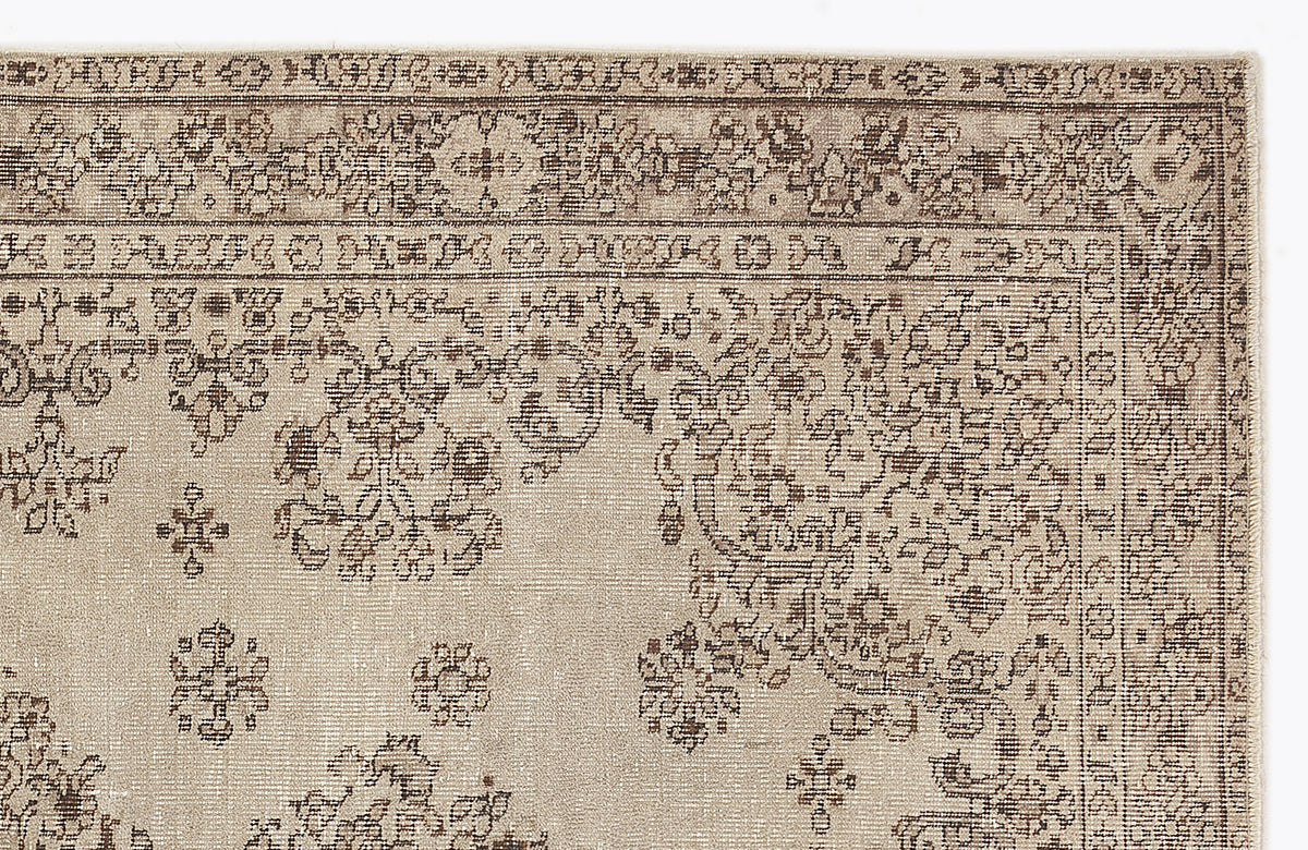 Beige and brown traditional rug with a distressed floral medallion pattern and a detailed geometric border.