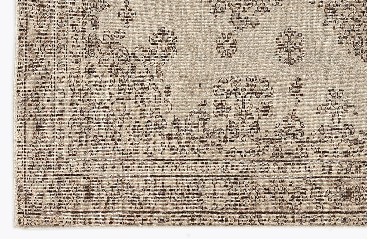 Beige and brown rug with a distressed traditional floral medallion pattern and a geometric border.