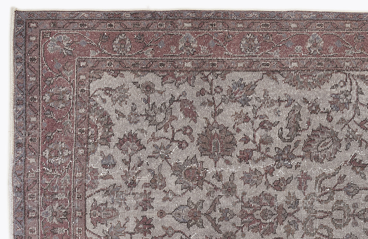 Distressed mauve and grey traditional rug with a floral medallion border and intricate botanical pattern.