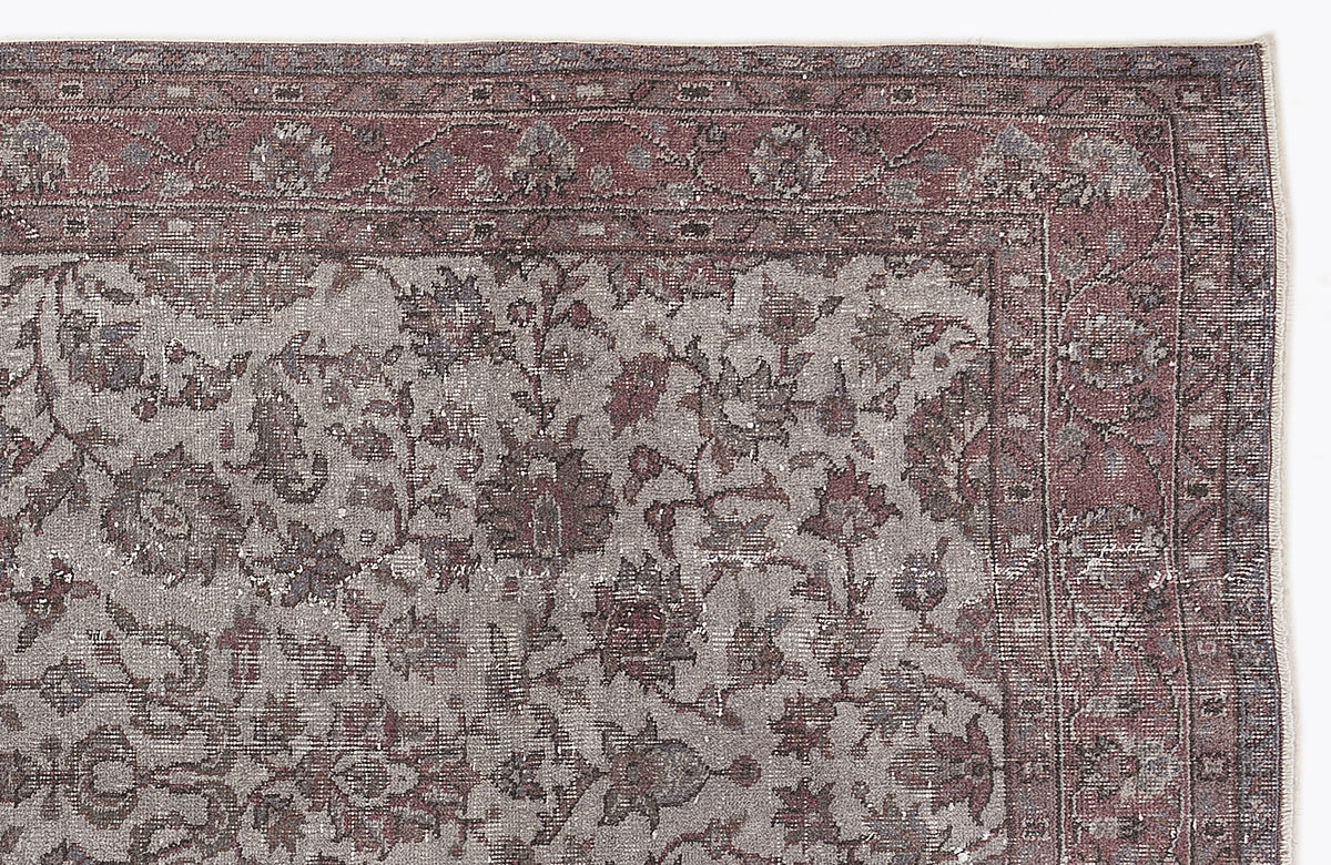Muted mauve and grey traditional rug with a distressed floral pattern and a detailed border.