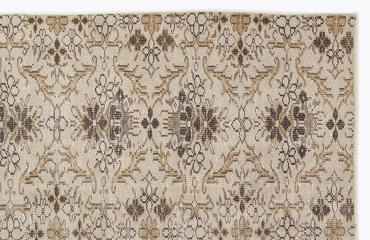 Beige rug with a repeating dark brown and tan floral medallion pattern in a distressed, vintage style.