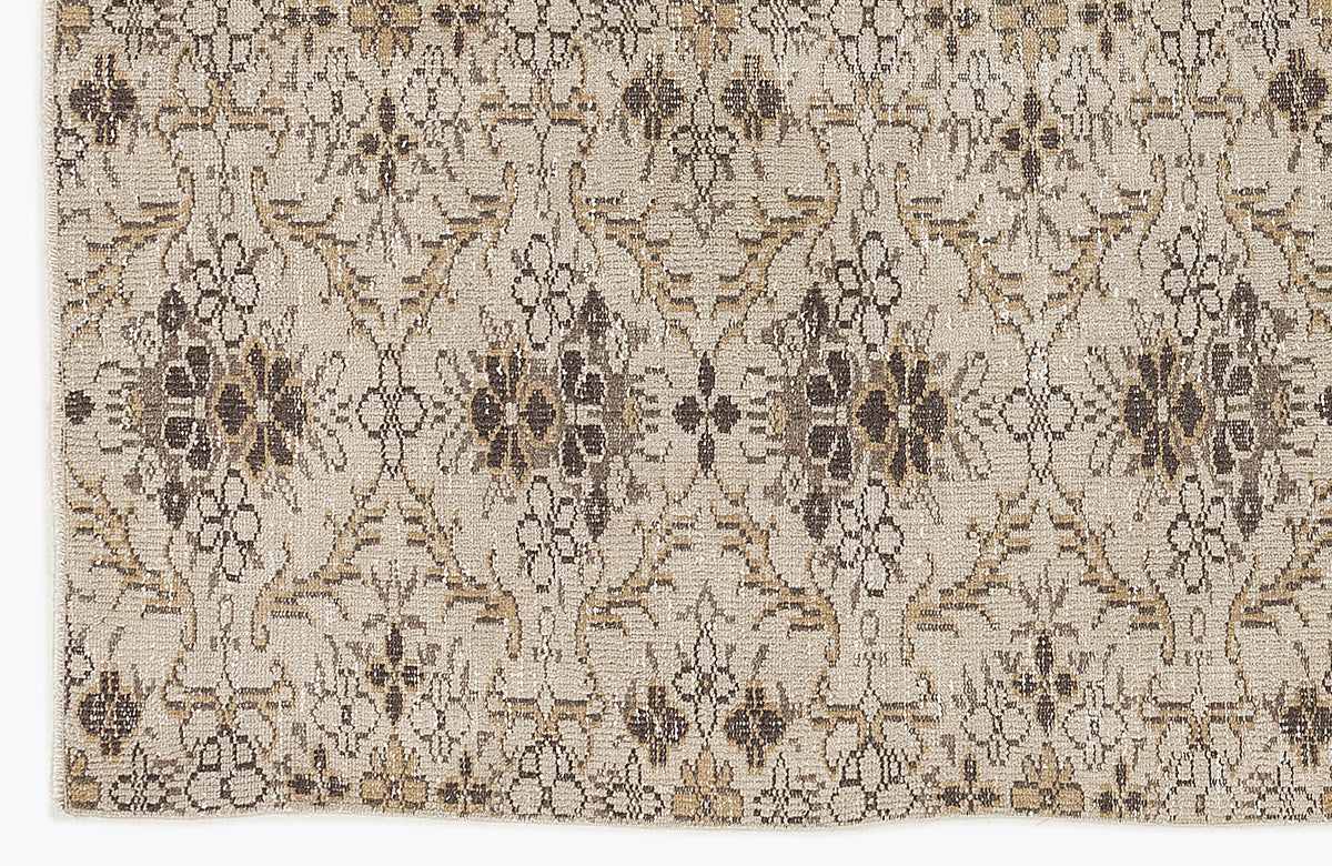 Beige and brown rug with a distressed, repeating floral medallion pattern.