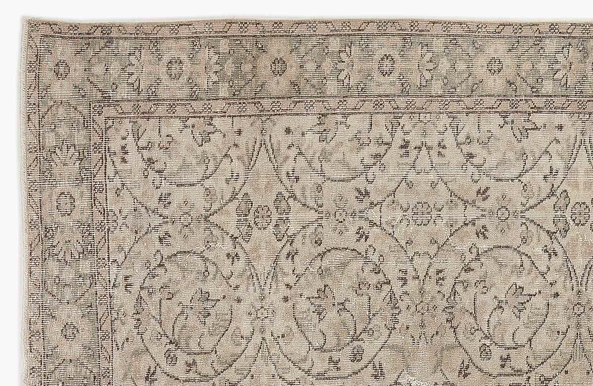 Beige and taupe vintage-style rug with a distressed floral medallion pattern and a detailed border.