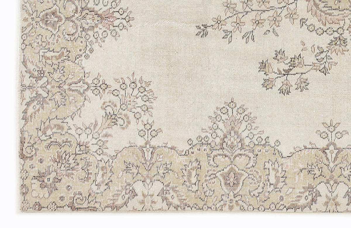 Cream and beige rug with a faded, distressed floral medallion pattern.