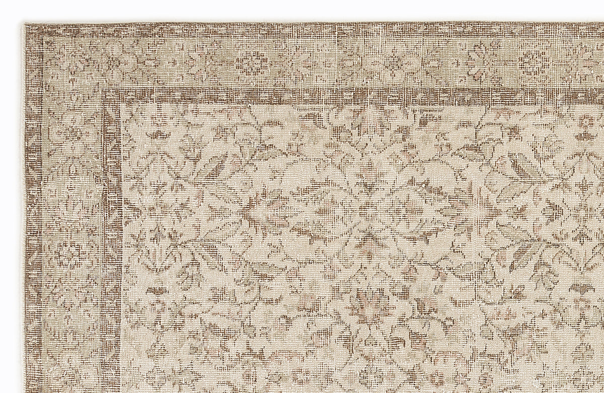 Beige and brown traditional rug with a distressed floral medallion pattern and a geometric border.