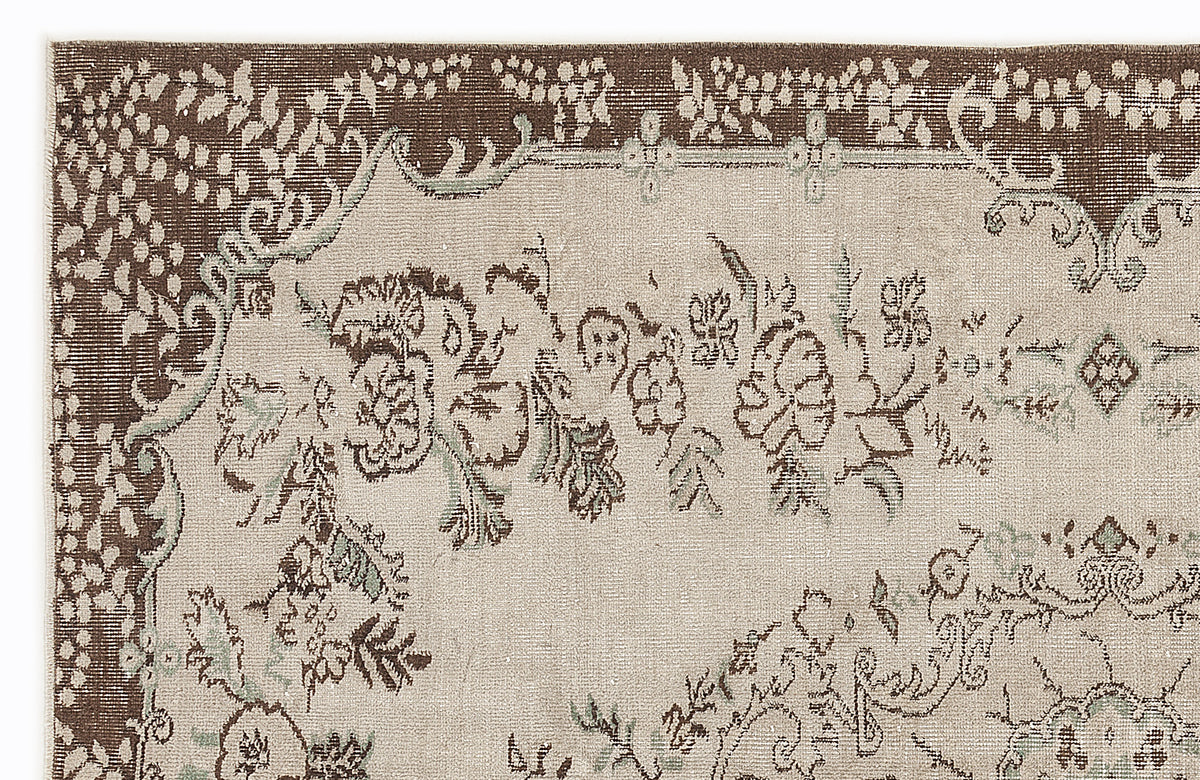 Brown and beige rug with a distressed floral medallion pattern and intricate border details on a white background.