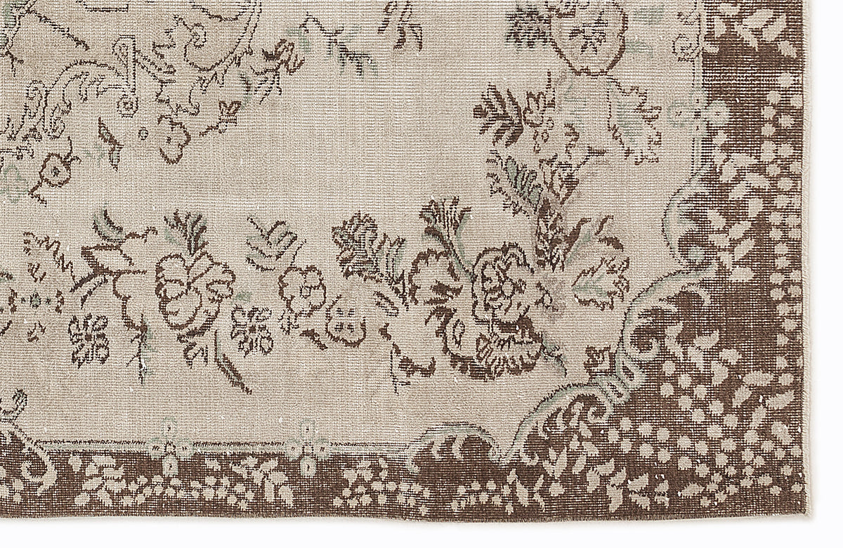 Beige and brown rug with a distressed floral medallion pattern and a wide decorative border.