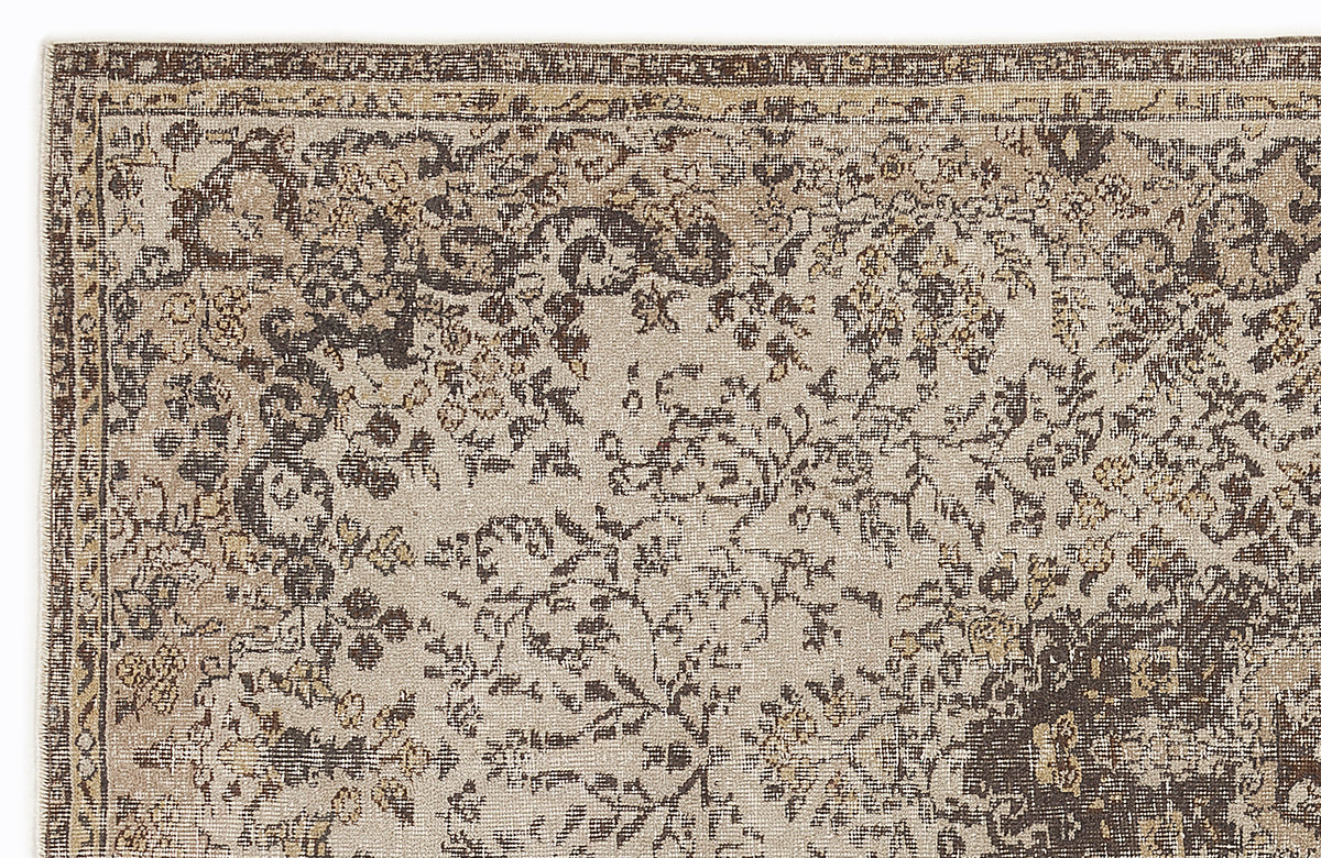 Beige and dark brown rug with a distressed, traditional floral pattern and a bordered edge.