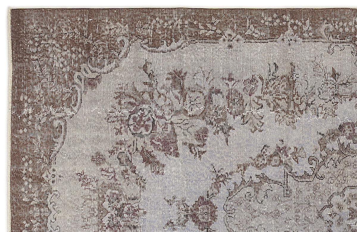 Distressed brown and light grey rug with a traditional floral medallion pattern and ornate border.
