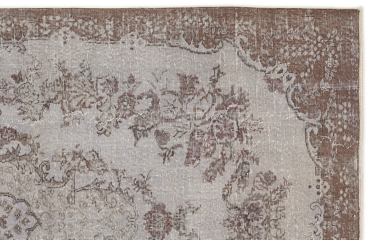 Brown and light grey distressed rug with a traditional floral medallion pattern.