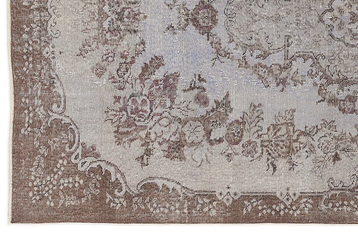Distressed brown and light blue rug with a traditional floral medallion pattern and ornate border.