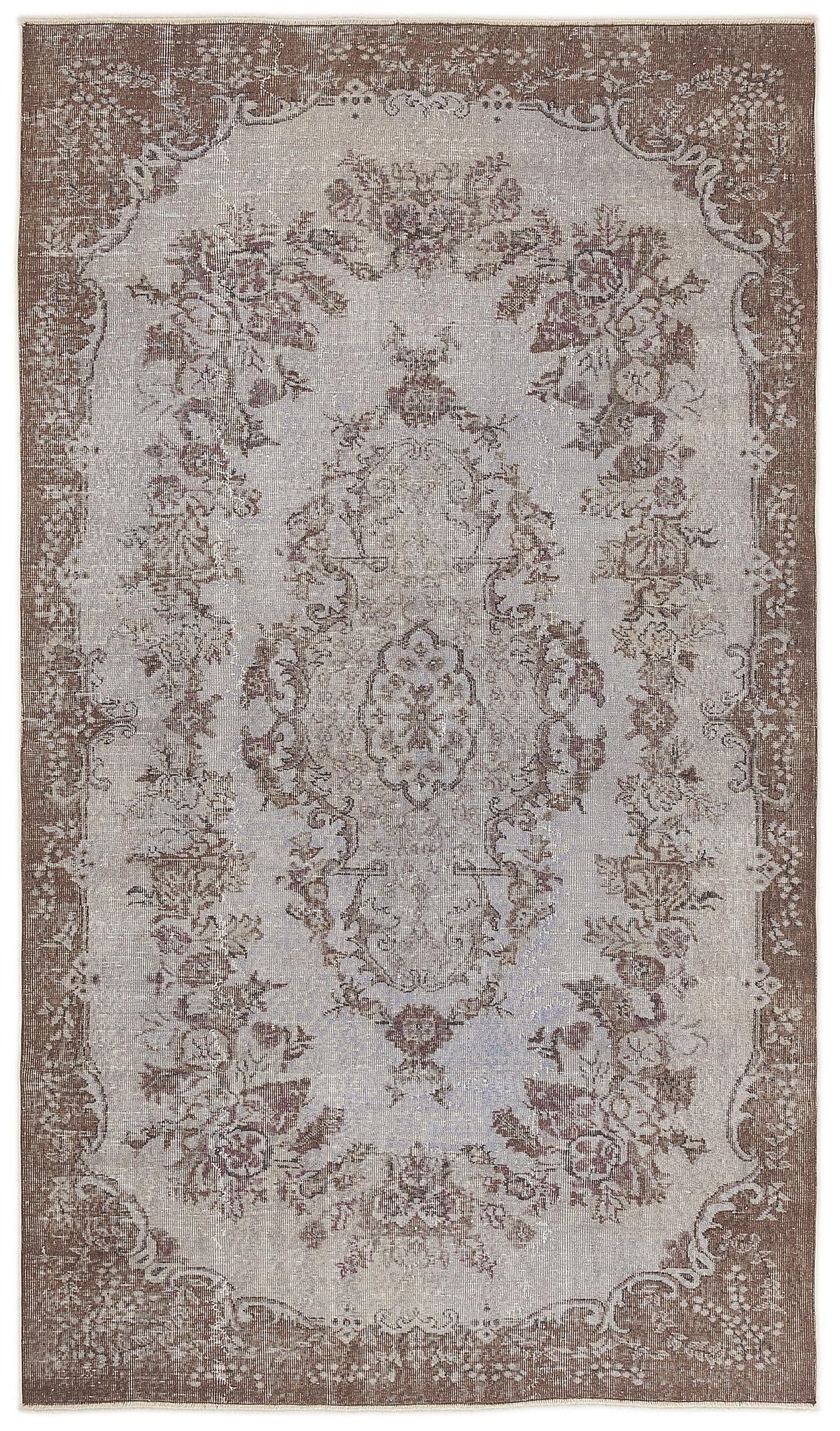 Brown and light grey distressed rug with a central floral medallion and ornate border pattern.