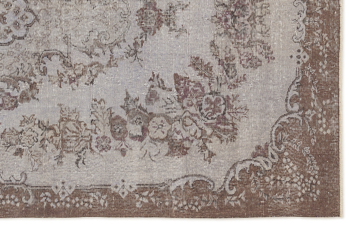 Distressed grey and brown rug with a traditional floral medallion pattern and a wide decorative border.