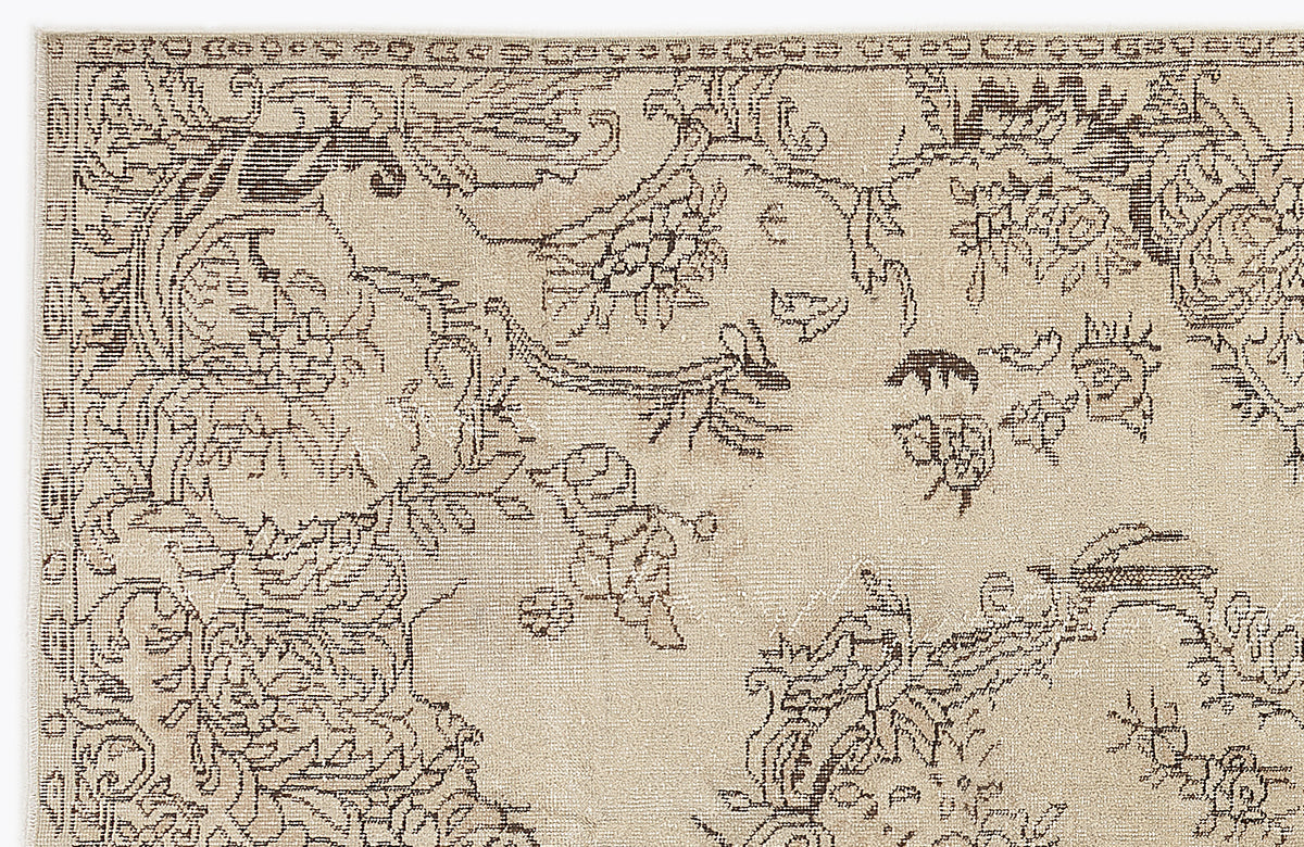 Beige rug with a dark brown distressed floral and vine pattern and a decorative border.
