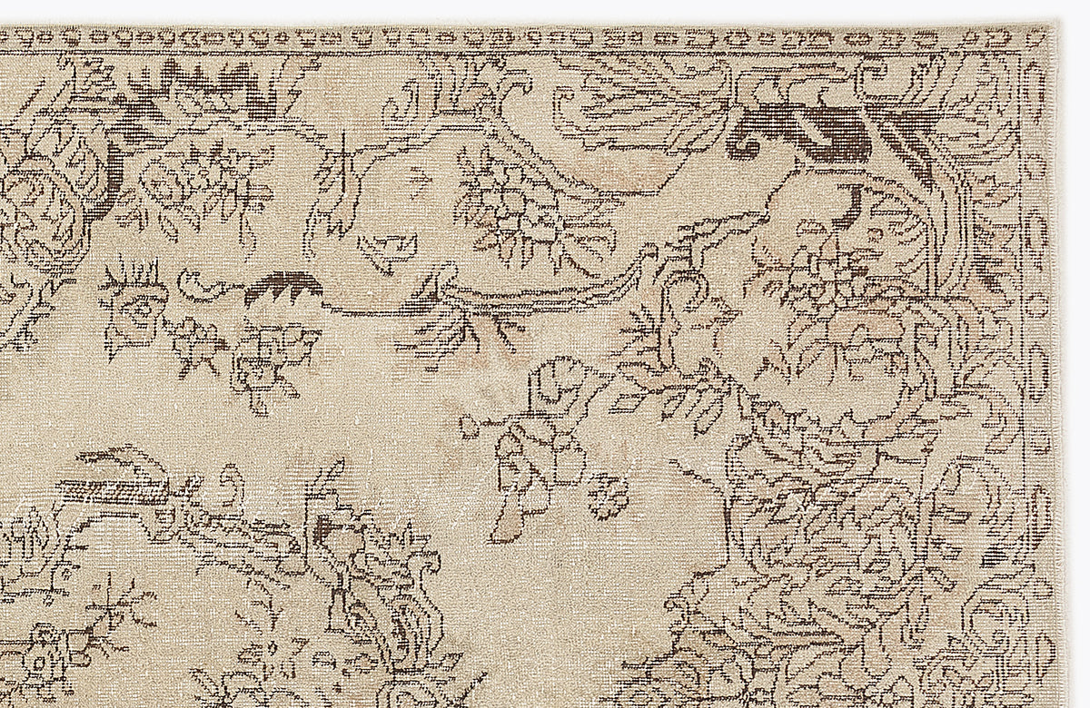 Beige rug with a dark brown traditional floral and vine pattern on a white background.
