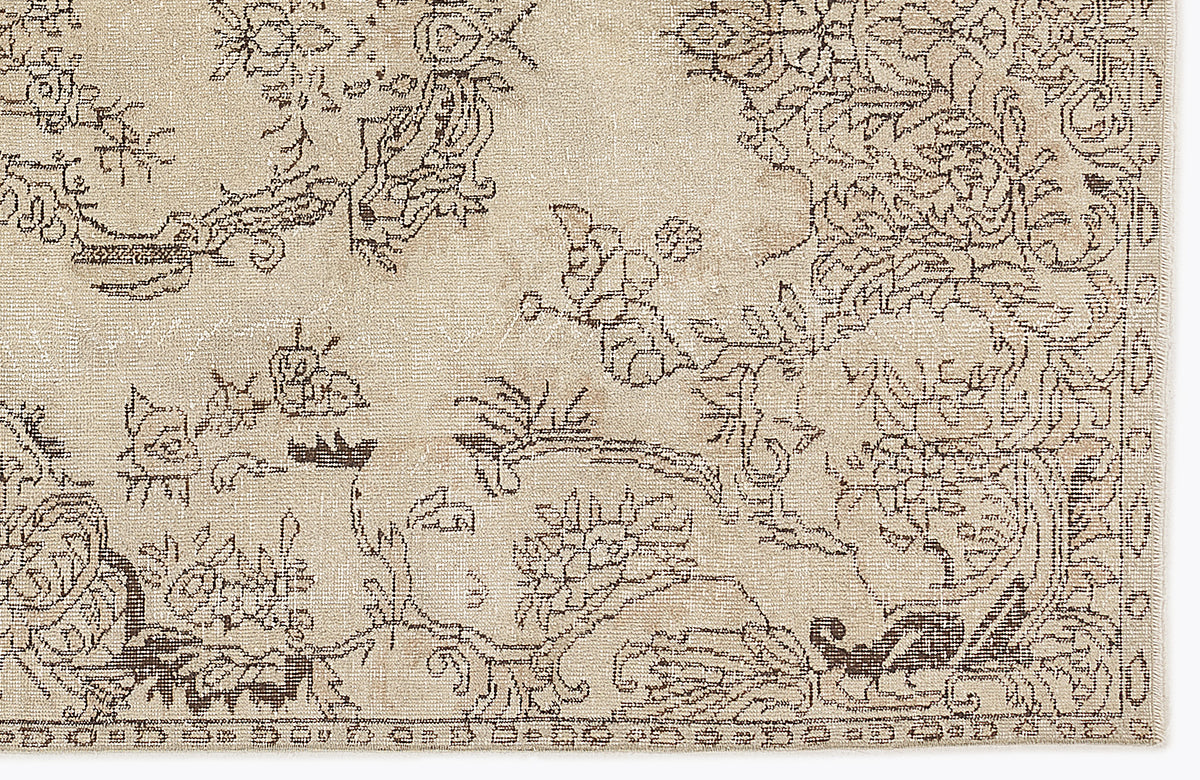 Beige rug with a dark brown distressed floral and vine pattern.