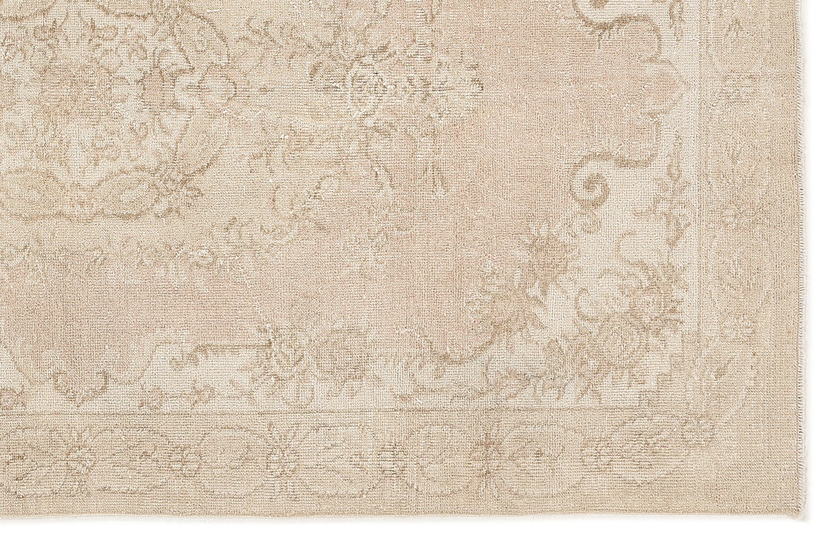 Beige monochromatic rug with a subtle, distressed traditional floral medallion pattern and a bordered edge.