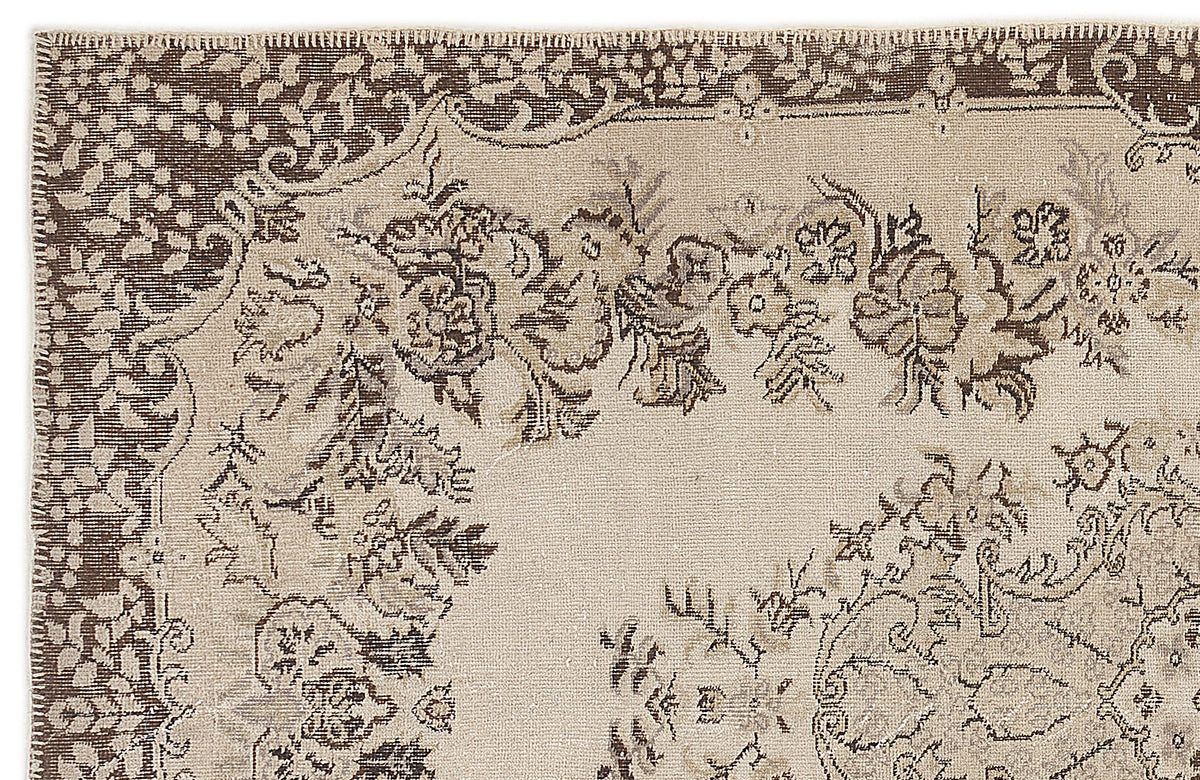 Beige and dark brown rug with a distressed floral medallion pattern and a decorative border.