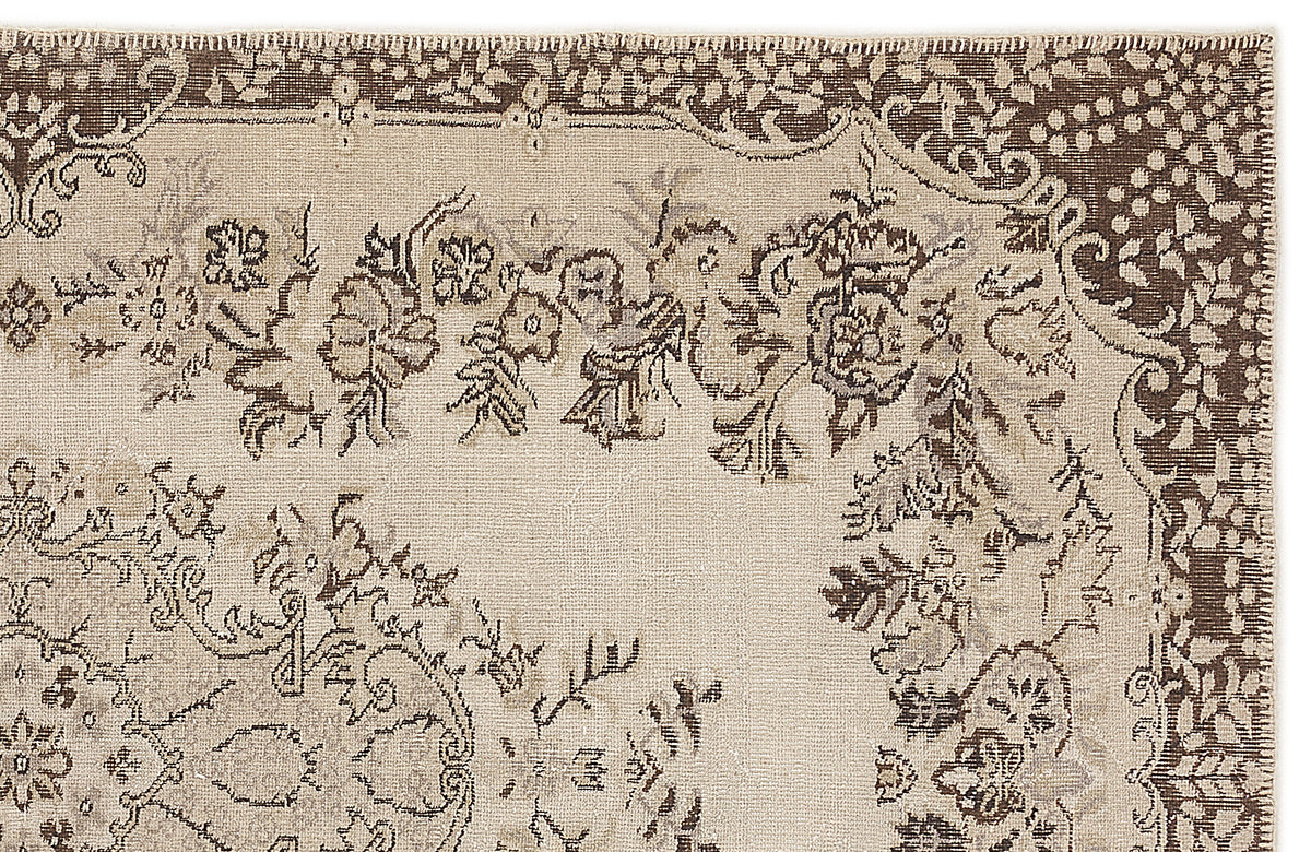 Beige and brown traditional rug with a distressed floral medallion pattern and a stitched border.