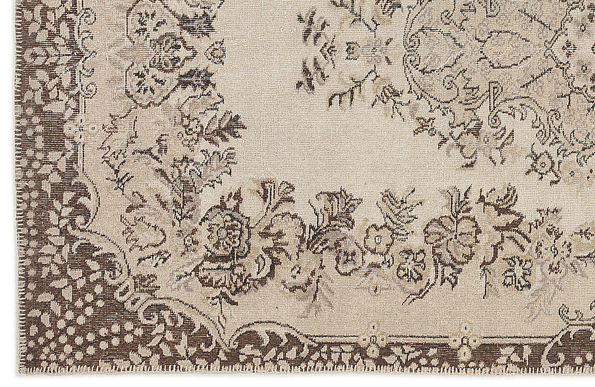 Beige and dark brown rug with a distressed traditional floral medallion pattern.