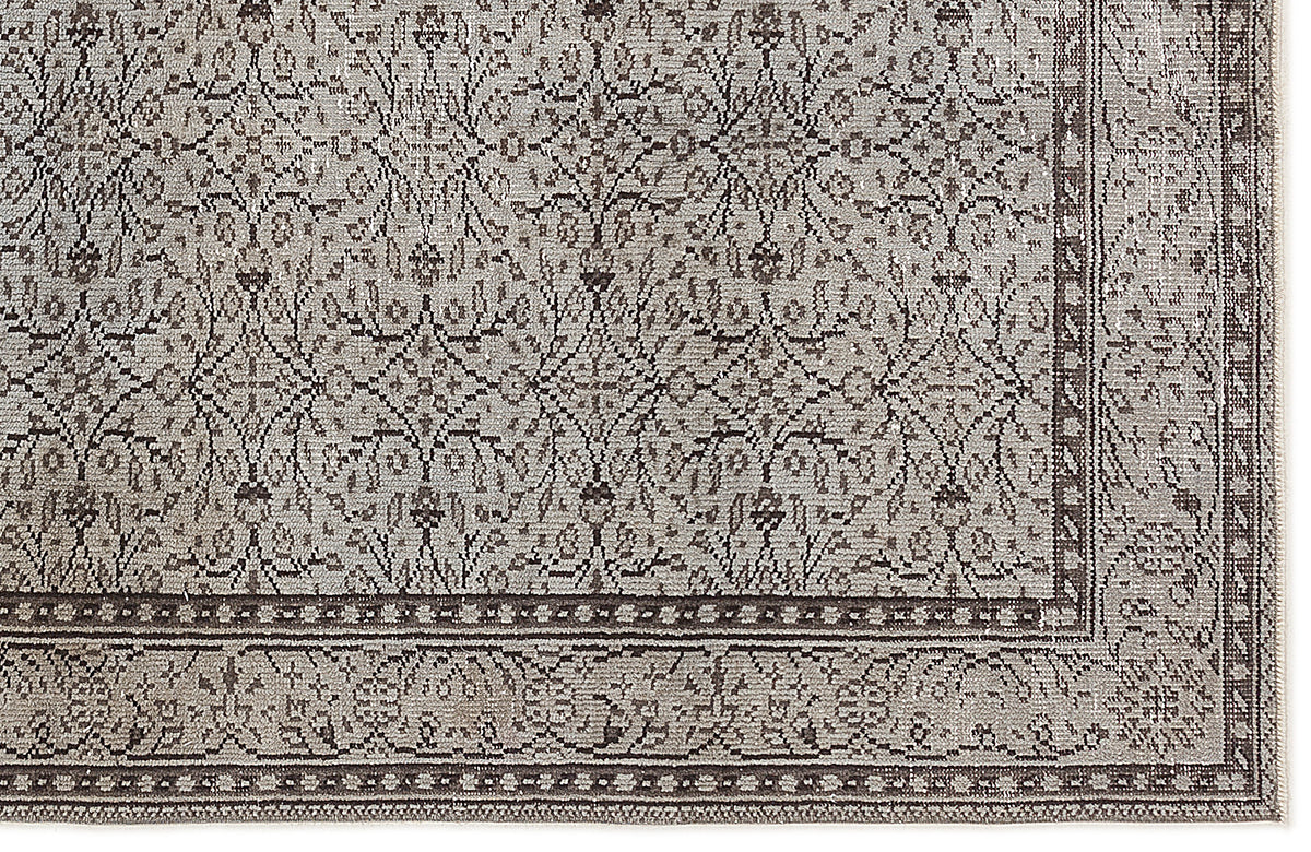 Taupe and charcoal rug with a traditional distressed floral pattern and a detailed geometric border.