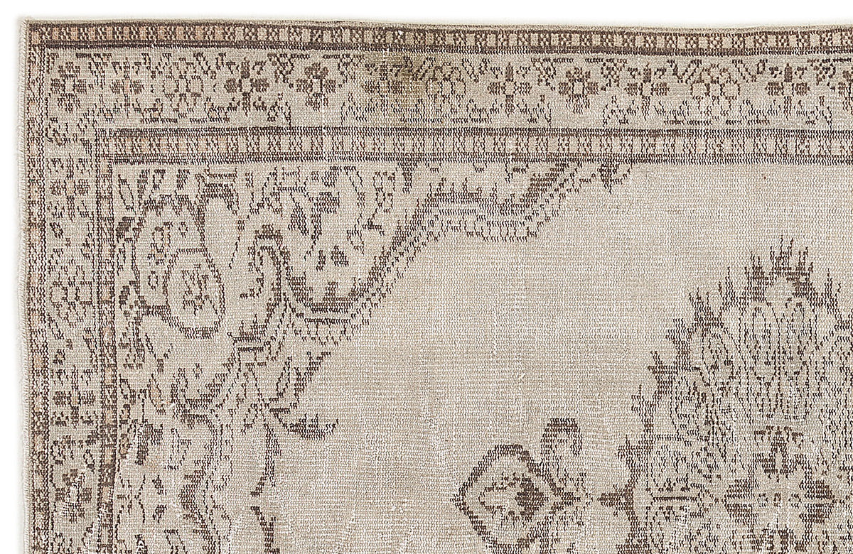 Beige and brown vintage-style rug with a distressed floral medallion pattern and a decorative border.