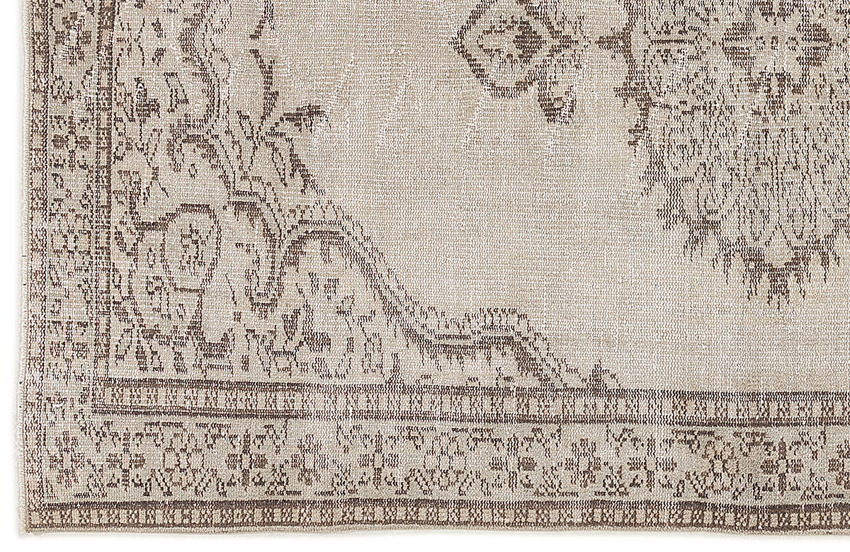 Beige and taupe distressed rug with a traditional ornate medallion pattern and a detailed geometric border.