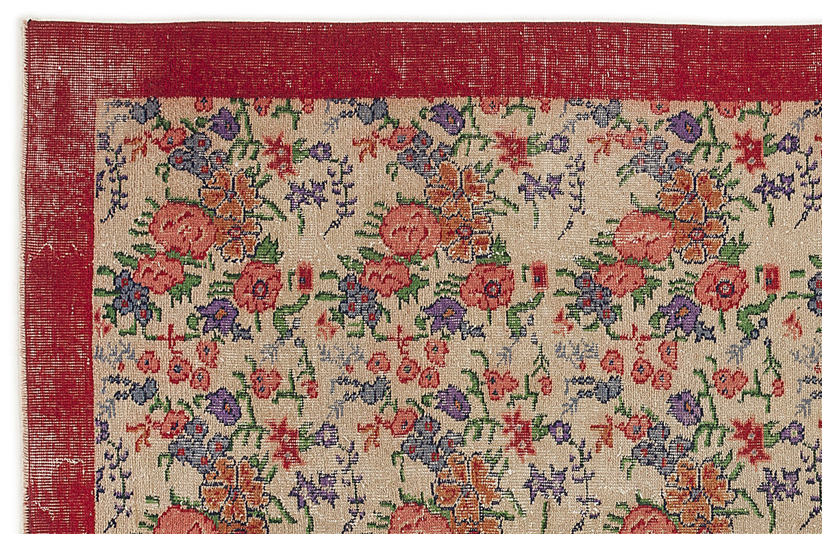 Beige rug with a red border and a repeating floral pattern in red, orange, purple, and green.