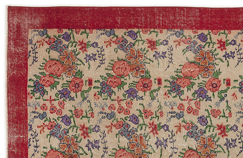 Load image 1 in gallery view. Beige rug with a red border and a repeating floral pattern in red, orange, purple, and green.