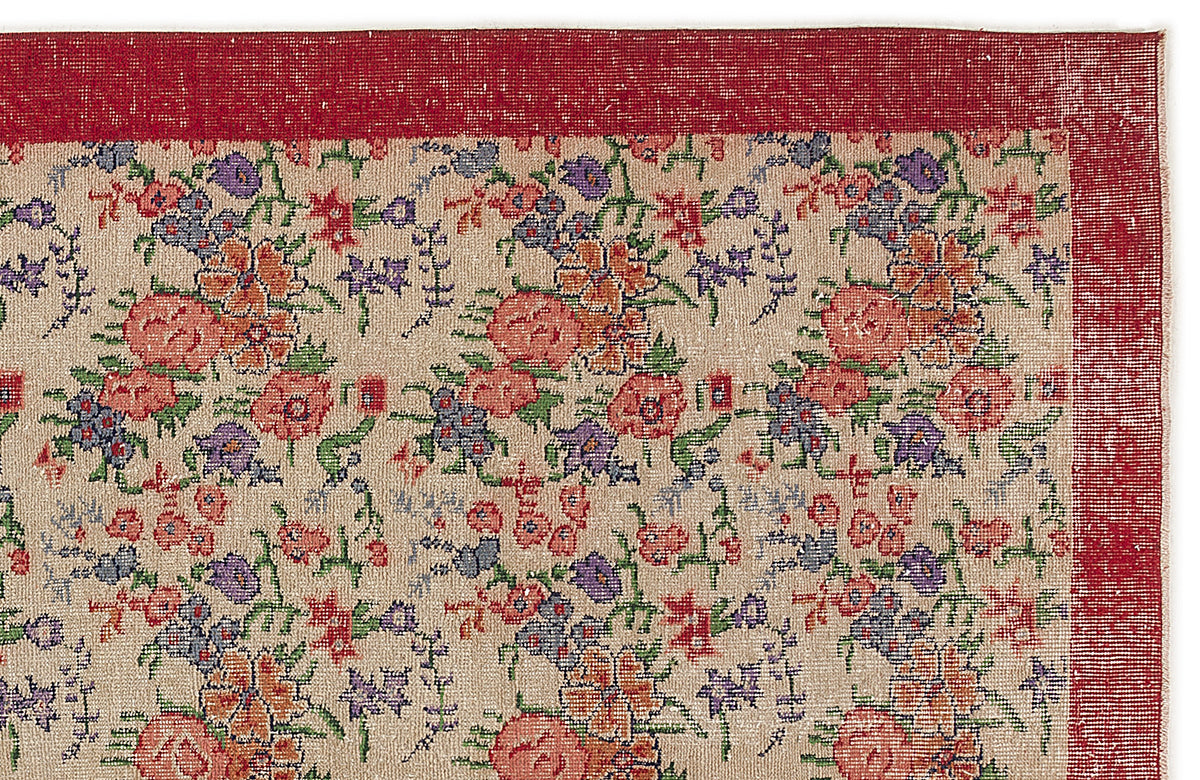 Beige rug with a red border and a multi-colored floral pattern in shades of pink, purple, orange, and green.