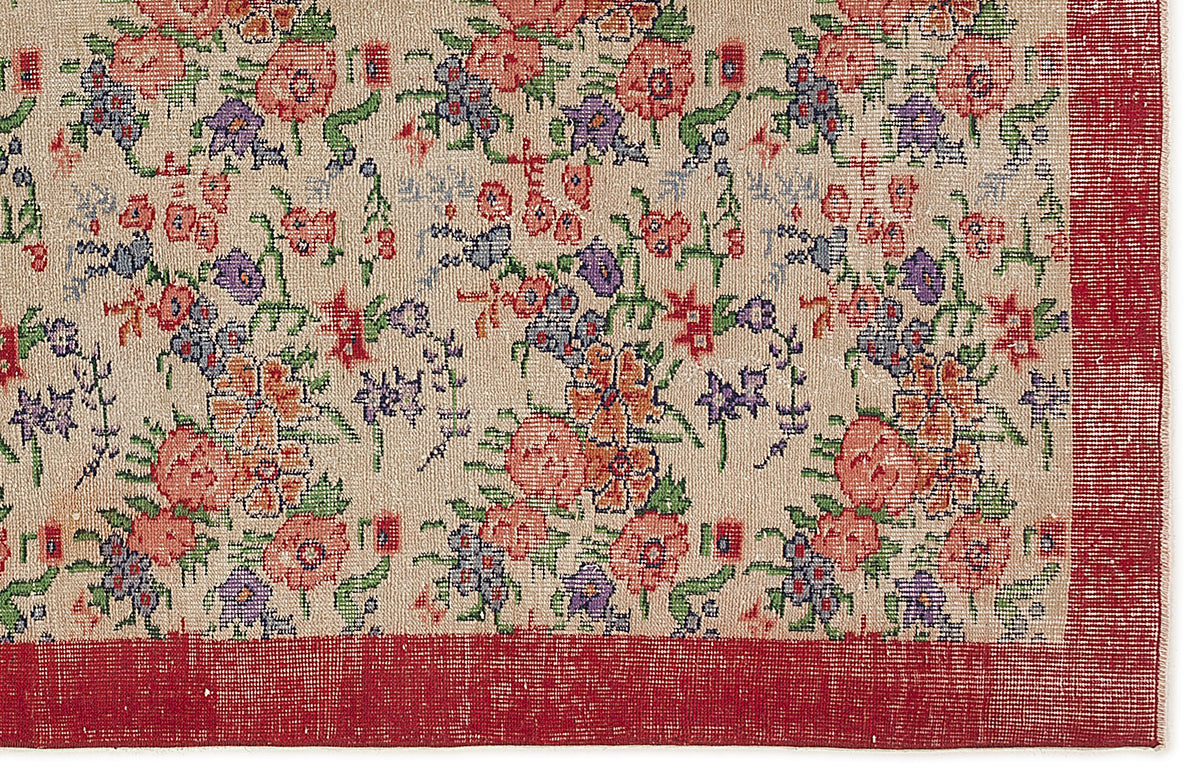 Beige rug with a multi-colored floral pattern in red, purple, and green, featuring a solid red border.