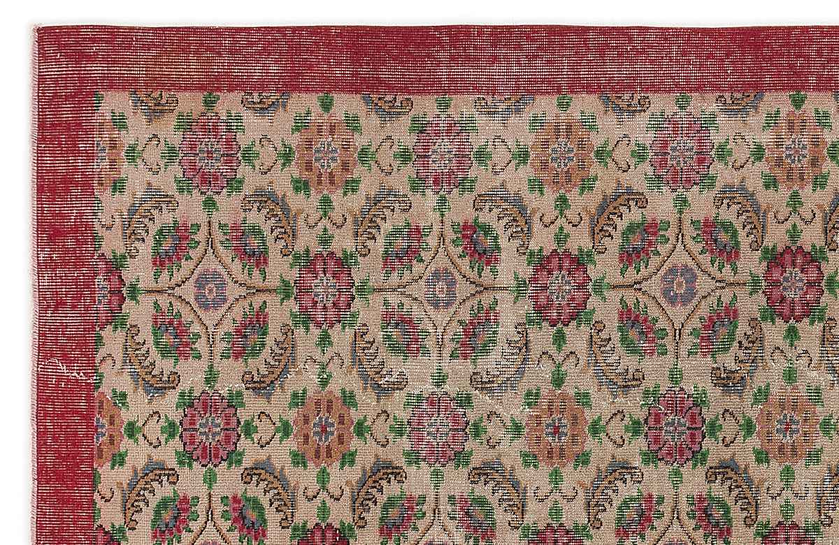Beige rug with a red border and a repeating floral medallion pattern in red, green, and blue on a white background.