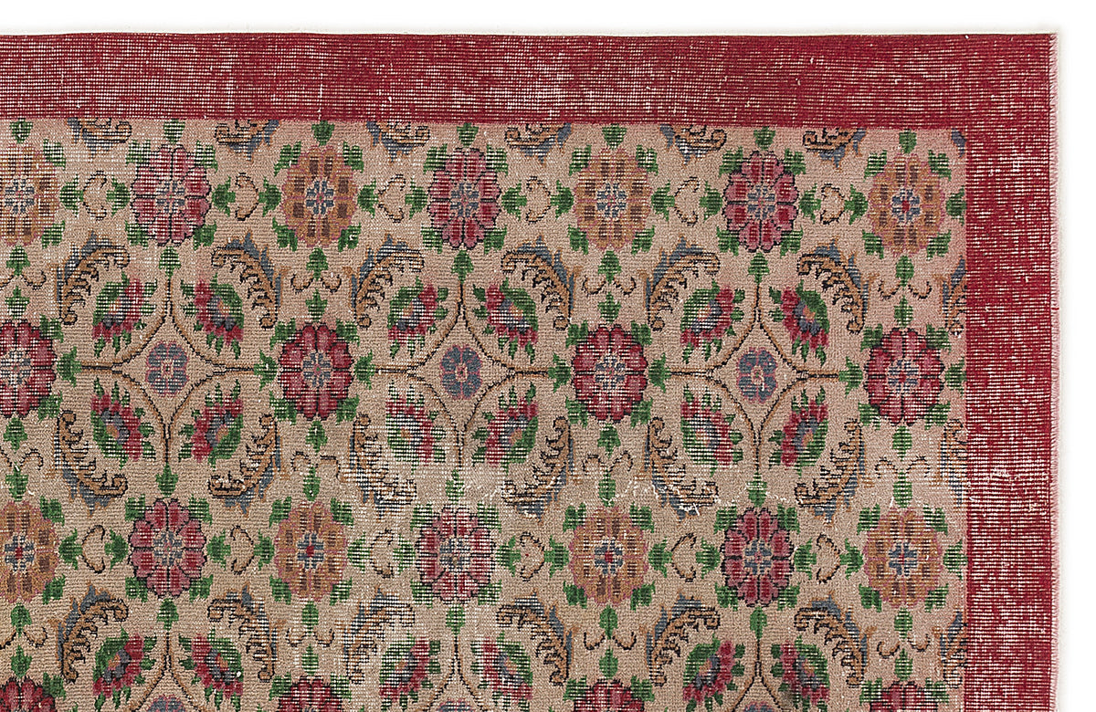 Beige rug with a red border and a repeating floral medallion pattern in red, green, and blue on a white background.