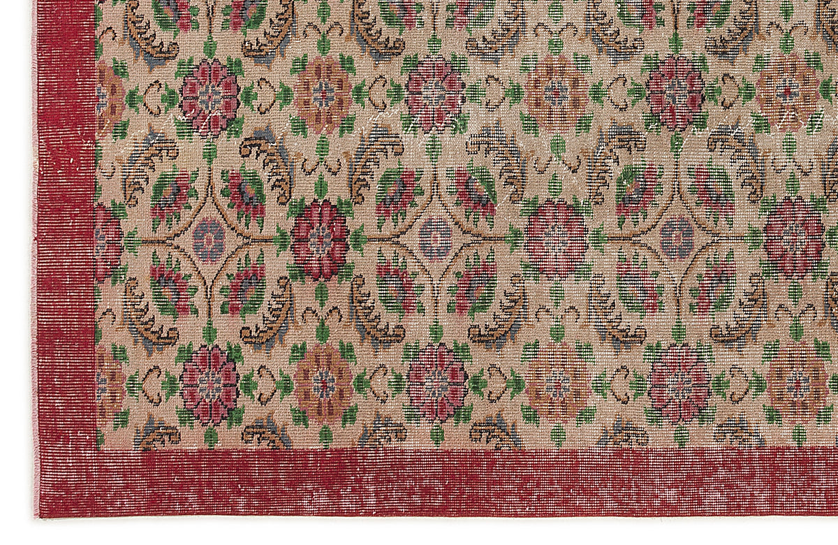 Beige rug with a repeating floral medallion pattern in red, green, and blue, featuring a wide red border.