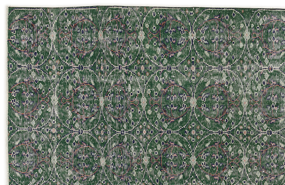 Dark green rug with a repeating circular medallion pattern in distressed white, blue, and pink tones.
