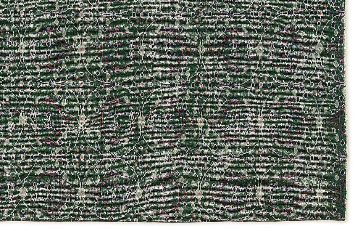 Dark green rug with a repeating circular medallion pattern in distressed white, blue, and pink accents.