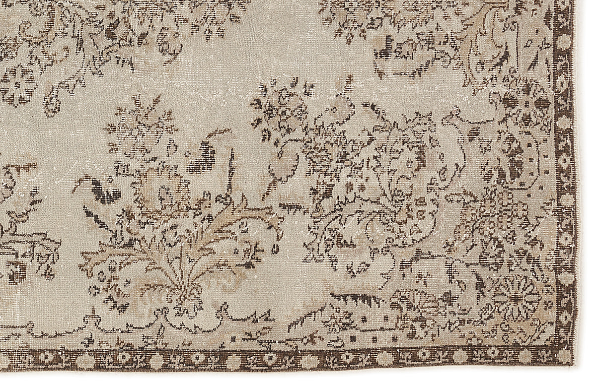 Beige and brown distressed rug with a traditional floral pattern and a decorative border.