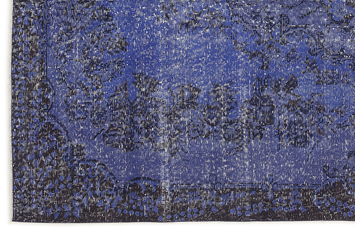 Deep blue and black distressed rug with a faded traditional floral medallion pattern.