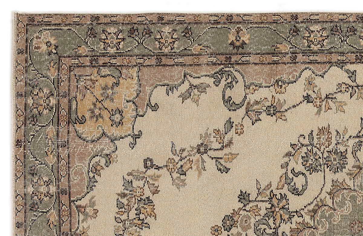 Beige rug with a sage green and brown floral border and central vine motif in a traditional style.
